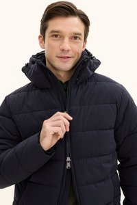 Marineblauer, gesteppter Pufferjacke mit Reißverschluss und verstellbarem Kapuze. Hat eine strukturierte Oberfläche und flache Reißverschlüsse.