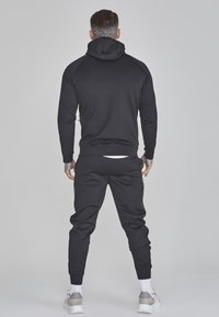 Set aus schwarzem Hoodie und Sweatpants, ausgestattet mit Kapuze, langen Ärmeln, gerippten Bündchen und bestickten Seitenakzenten, mit einer glatten Textur.