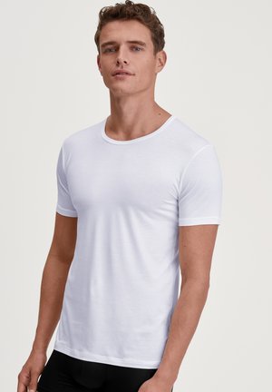 T-shirt bianco a maniche corte realizzato in tessuto leggero con scollatura rotonda e superficie liscia, caratterizzato da un design aderente su uno sfondo neutro.