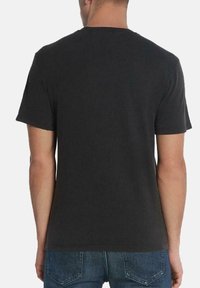 Camiseta de algodón negra de manga corta, con cuello redondo y un diseño liso, vista desde la parte posterior. Fabricada en un tejido ligero y con un corte relajado.