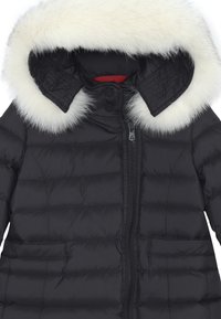 Giubbotto imbottito nero con chiusura a zip, dotato di cappuccio in pelliccia sintetica bianca removibile, design a righe orizzontali e tasche laterali.