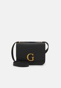 Černá kožená crossbody taška se zlatým „G“ zapínáním a nastavitelným popruhem na bílém pozadí.