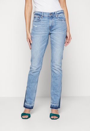 Jeans de denim azul claro con corte recto, con bordes deshilachados y aberturas laterales; diseño clásico de cinco bolsillos con pasadores para cinturón.