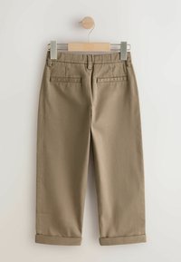 Khaki színű nadrág egyenes szárú kialakítással, felhajtott szegéllyel és két hátsó zsebbel, sima anyagból készült. Fából készült vállfán lóg.