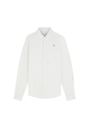 Valkoinen pitkähihainen nappikauluspaita, jossa on ohuita pystysuoria raitoja ja pieni tumma pääkallo-logo vasemmassa rinnassa.