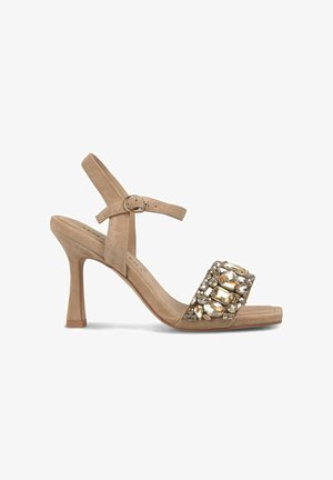 Sandales à talons en suede beige avec une large bride ornée d'accents transparents et dorés, et une fine bride de cheville réglable.