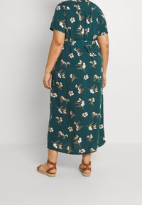 Groene bloemen midi-jurk met korte mouwen, tailleband en vlinderaccenten. Beschikt over een vloeiende stijl met een soepele textuur.