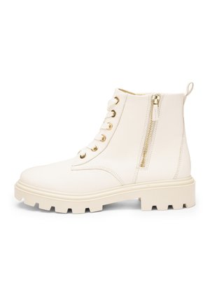 Enkellaars in crèmekleur met dikke profielzool, veterlus aan de voorkant, gouden oogjes, ritssluiting aan de zijkant en een trekriempje bij de hiel.