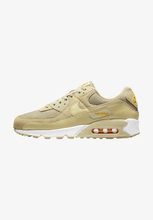 Beige Nike Air Max sneaker met mesh, leren panelen, zichtbare luchtkussen in de zool en gele merkdetails op witte achtergrond.