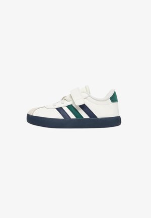 Sneaker bianca con suola blu navy, strisce laterali blu navy e verdi, cinturino in velcro e linguetta verde sul tallone.