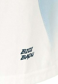 Weißer Stoff mit einem hellblauen Einsatz. Besitzt ein bedrucktes Logo "BIDI BADU" in Dunkelblau am Saum. Glatte Textur, maßgeschneidertes Design.