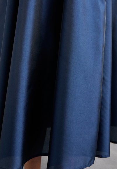 Falda azul marino confeccionada en un tejido ligero, con una textura suave y una silueta amplia en forma de A, con el dobladillo que termina a mitad de pantorrilla.
