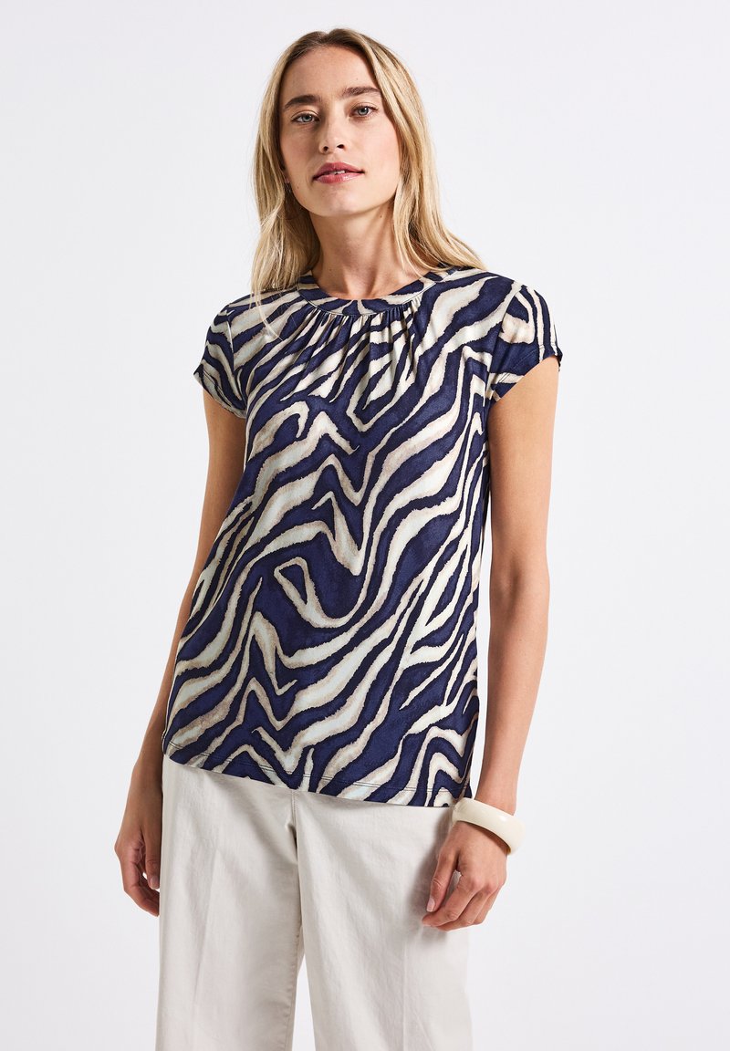 Top corto a maniche corte blu navy e crema con motivo a strisce di zebra e scollatura arricciata, realizzato in un tessuto leggero e texturizzato.