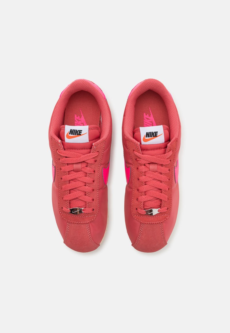 Baskets Nike rose avec une tige en mesh et en daim, lacets plats, swoosh rose contrastant et un logo blanc sur la languette. Semelle en caoutchouc.