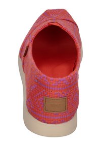Jasně oranžová tkaná obuv na slip-on s texturovaným vzorem, červený interiér a hnědý obdélníkový štítek s nápisem "TOMS" na patě.