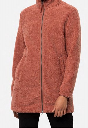 Rustkleurige lange fleecejas met rits aan de voorkant en zijzakken, gedragen door een persoon met een donkere broek en één zichtbare hand.