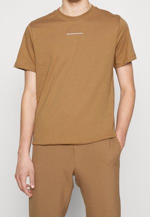 Brun bomulds T-shirt med korte ærmer og rund hals, prydet med hvid "SANDRO PARIS" tekst trykt på forsiden. Glat tekstur.