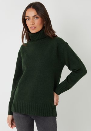 Dunkelgrüner Rollkragenpullover aus weichem, strukturiertem Stoff. Verfügt über gerippte Bündchen und Saum sowie eine lockere Passform.