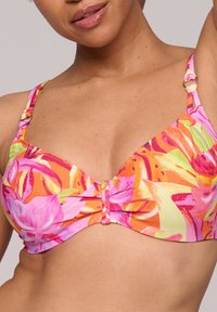 Värikäs bikinitoppi, jossa on kukkakuosi vaaleanpunaisena, oranssina ja vihreänä. Siinä on säädettävät hihnat ja keskellä solmu.