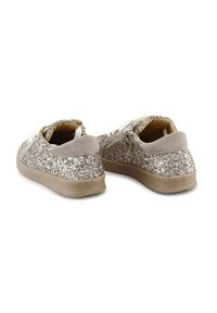Zapatillas beige brillantes con parte trasera de ante, cordones blancos y suela de goma texturizada. La parte superior está cubierta de destellos plateados.