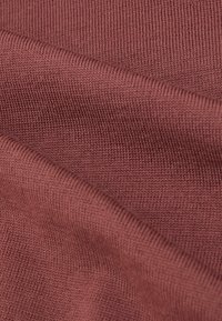 Tkana dzianina rypsowa w kolorze rdzy o gładkiej fakturze, z delikatnymi wzorami dzianiny i lekkim rozciągnięciem, złożona w warstwy.