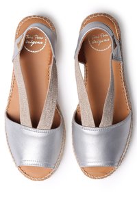 Sandali aperti in metallo argento con cinturini elastici e soletta in pelle naturale. I dettagli in corda attorno alla suola aggiungono texture.