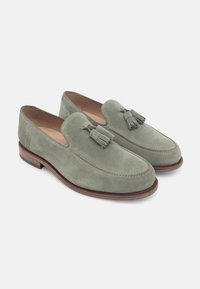Suede loafers in een gedempt groen met kwastjes, instapontwerp, ronde neus, bruine leren zool en contrasterende stikdetails.