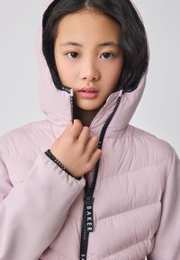 Lys pink dunjakke med hætte, med lynlåslukning, elastiske manchetter og sorte brandede detaljer. Glat, quiltet tekstur.