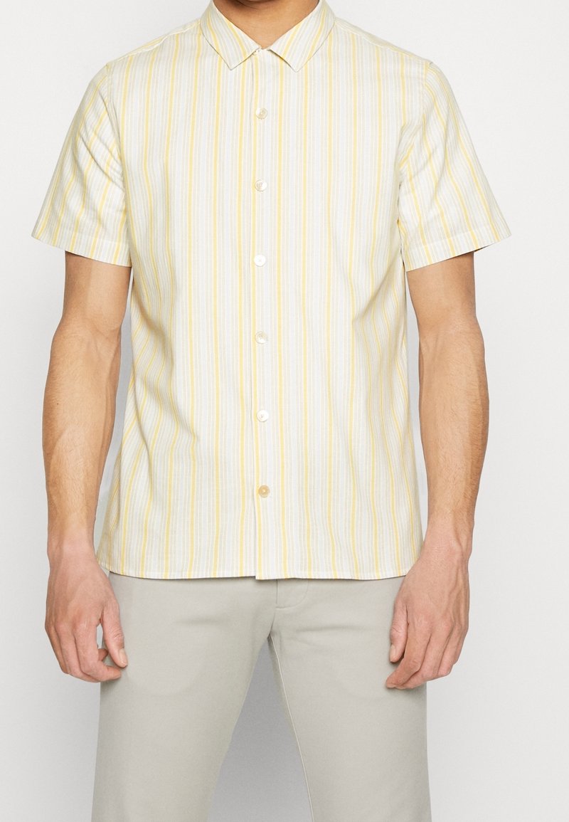 Camicia a maniche corte con bottoni in giallo chiaro e bianche righe verticali, con colletto classico e orlo dritto. Tessuto morbido.