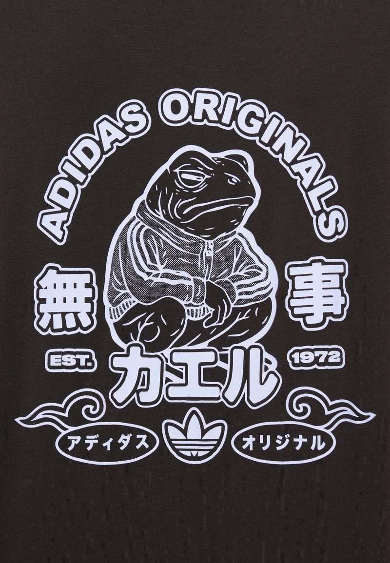 T-shirt noir avec un graphisme blanc représentant une grenouille en sweat à capuche, entourée de texte et de logos, dont "ADIDAS ORIGINALS" et des caractères japonais.