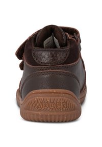 Scarpa alta in pelle scamosciata e cuoio marrone con strap in velcro, dettagli testurizzati e suola in gomma con un motivo rigato. Logo del marchio sul tallone.