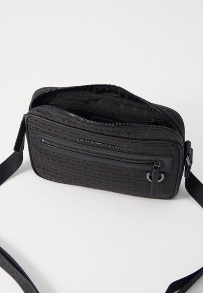 Black synthetic crossbody bag with embossed Emporio Armani logo, zip closure, adjustable strap, and a front pocket with zip detail.