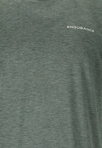 Camiseta deportiva de manga corta en color gris-verde, confeccionada con tejido transpirable, que presenta una sutil textura y la palabra "ENDURANCE" impresa en blanco.