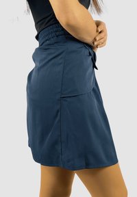 Falda azul marino hecha de tejido ligero, con una cinturilla elástica, bolsillo lateral y corte recto con una textura suave.