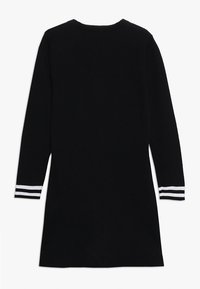 Mustapaitapuku, jossa on pitkät hihat, pyöreä kaula-aukko ja valkoiset raidat ranteissa. Sileä pinta ja polvipituinen muotoilu.