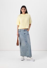 Gul strikket kortermet genser kombinert med en lys blå denim maxiskjørt. Hvite joggesko og en brun crossover bag er inkludert.