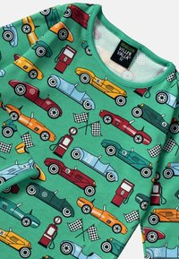 Vihreä puuvillapaita, jossa on autoaiheinen kuosi, jossa on erilaisia värisiä vintage-autoja, bensiinipumppuja ja ruutulippuja. Pyöreä pääntie ja pehmeä tekstuuri.
