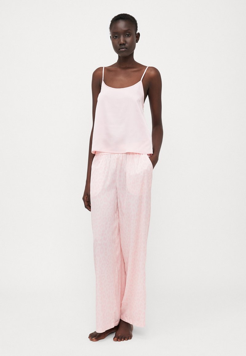 Camisole di raso rosa chiaro con spalline sottili, abbinato a pantaloni da pigiama larghi con una sottile stampa leopardata in una tonalità abbinata.