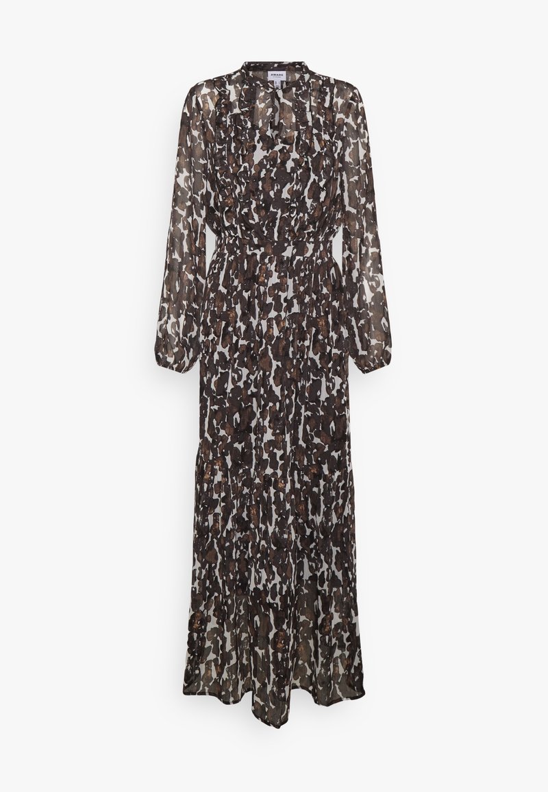 Lång, genomskinlig klänning i ett brunt och vitt prickigt mönster. Har hög halsringning, långa ärmar och en flödande silhuett.