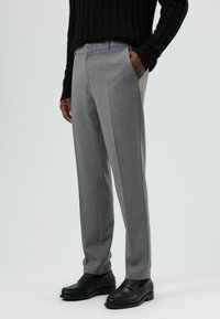 Grijze op maat gemaakte broek met een gladde textuur, voorzien van een rechte snit, zijzakken en een platte voorkant, gecombineerd met zwarte schoenen.