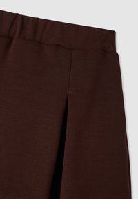 Gonna marrone al ginocchio con una texture liscia, vita elastica e un delicato dettaglio a pieghe frontali.