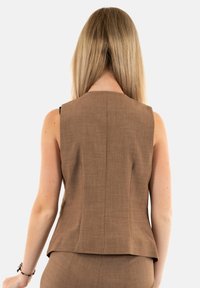 Top senza maniche marrone con un design strutturato, texture liscia e un sottile motivo intrecciato. Presenta un retro dritto e una vestibilità sartoriale.