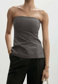 Haut gris sans bretelles avec fines rayures blanches verticales, coupe ajustée et texture lisse. Associé à un pantalon sombre taille haute.