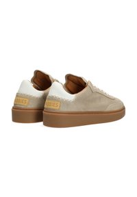 Baskets en suède beige avec un talon en cuir blanc et une semelle en caoutchouc tan. Présente des accents cousus et une étiquette en cuir tan marquée au dos.