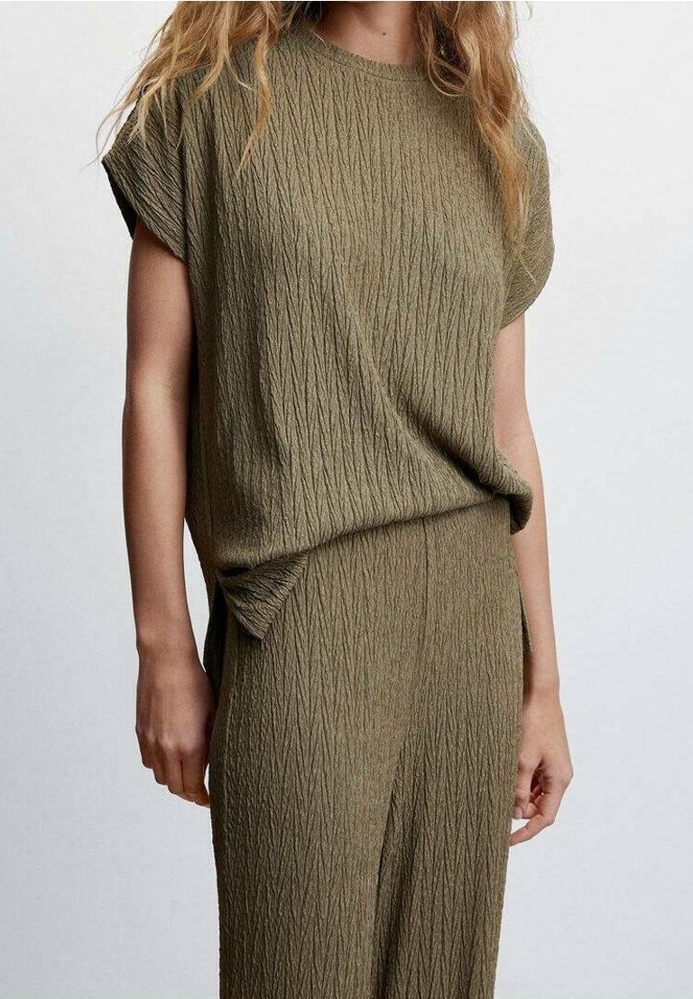 Haut en vert olive texturé avec des manches courtes et une coupe décontractée, présentant de légères rayures verticales. Assorti avec un bas texturé assorti.