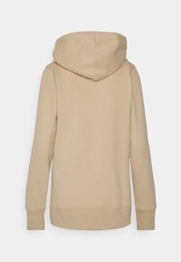 Sudadera con capucha beige de textura suave, mangas largas y una capucha grande. Presenta un diseño sencillo y puños y dobladillo acanalados.