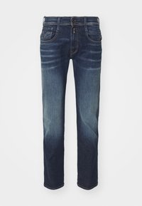 Mörkblå denimjeans med rak passform, subtila blekningar, fem fickor och dragkedja med knappstängning som visar lätta texturvariationer.