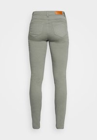 Slim-fit, högmidjade jeans i ljusgrön tyg med en slät textur, med en brun läderetikett vid bakre midjan och två bakfickor.