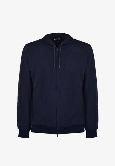 Marinblå zip-hoodie i mjukt tyg, med huva, ribbade ärmslut och strukturerade sidopaneler med logodetaljer på ärmarna.