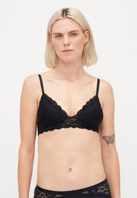 Black lace bralette featuring triangle cups, scalloped edges, adjustable straps, and a sheer, floral pattern. Lightweight, feminine design.
